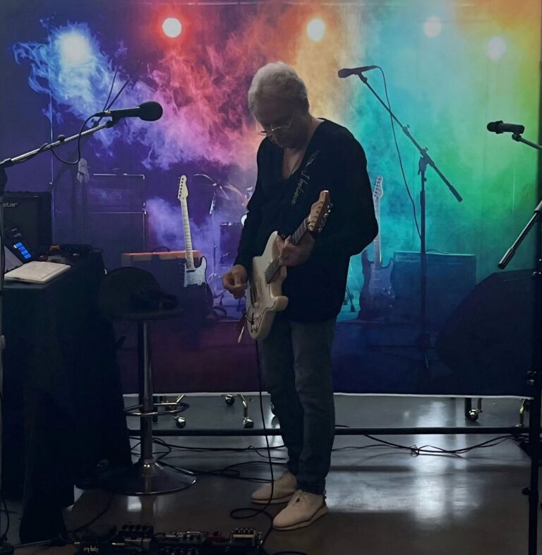 Guitarist performing on the studio stage in front of a colorful backdrop