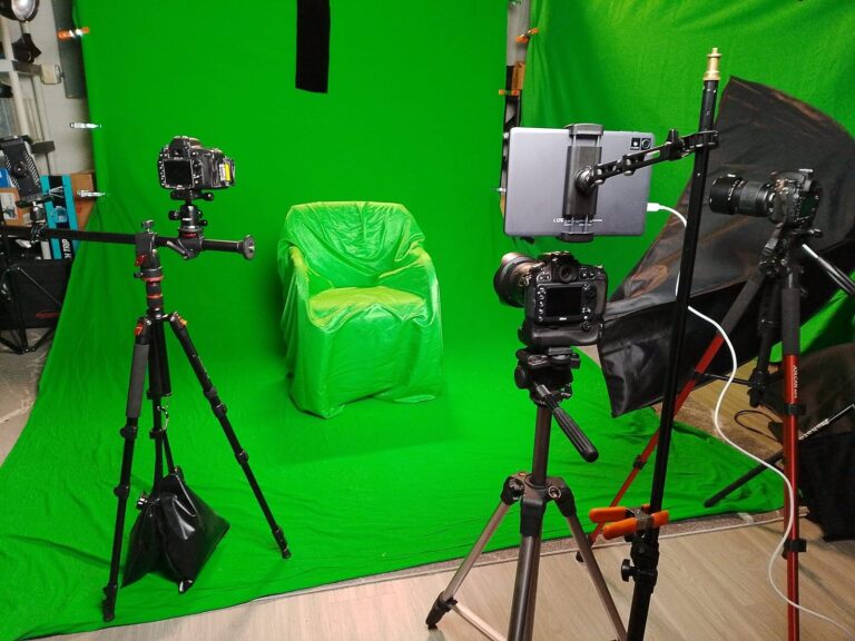 Multiple cameras on tripods aimed at a chair on the green screen