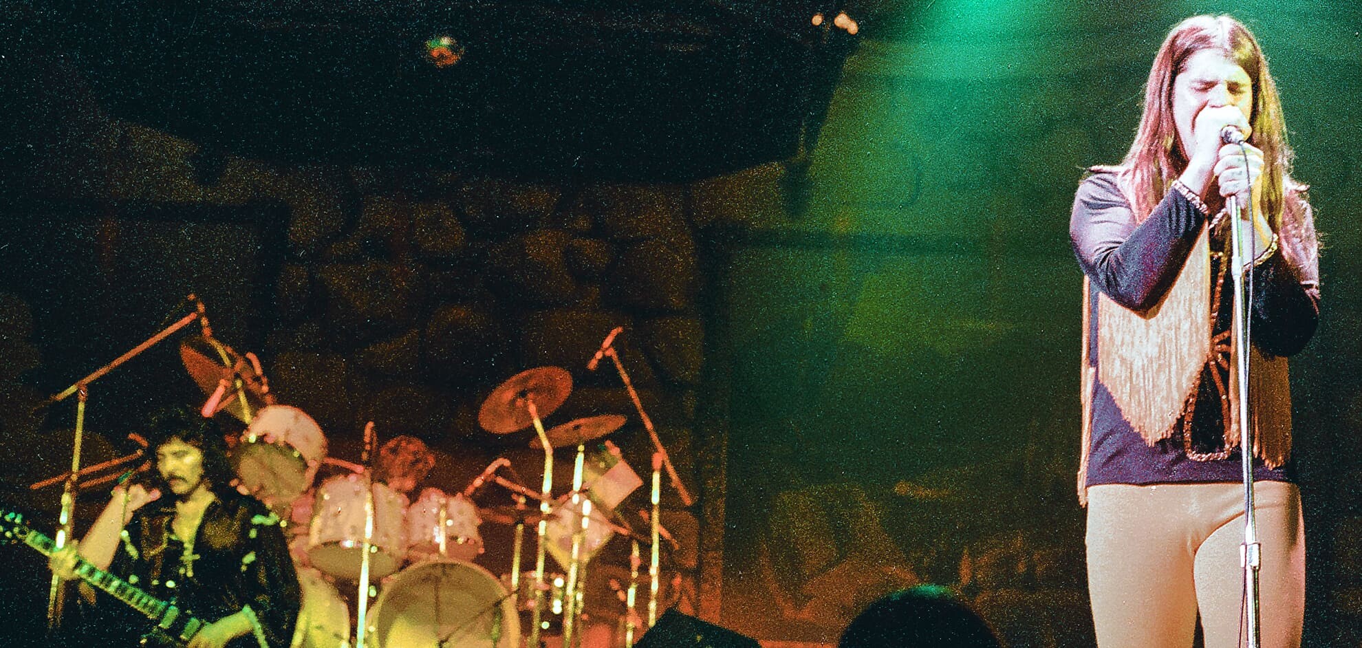 Rock band performing live on stage under green lights